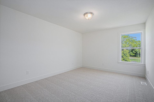 unfurnished room with visible vents, light carpet, and baseboards