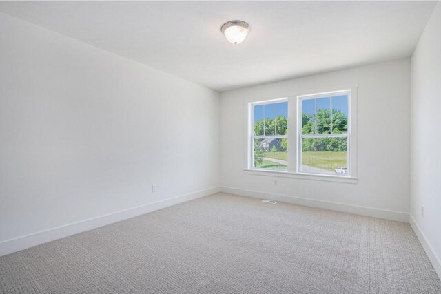 empty room featuring baseboards and light carpet