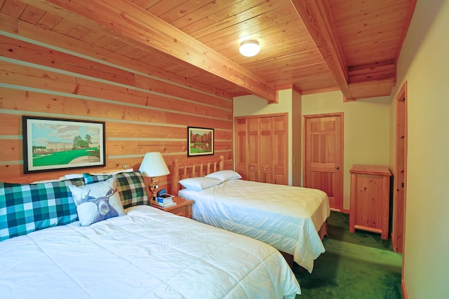 carpeted bedroom with beamed ceiling, wooden walls, two closets, and wood ceiling