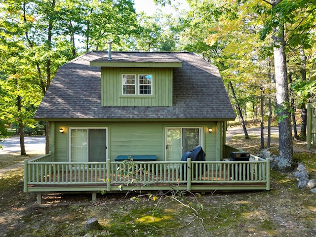 back of house featuring a wooden deck and roof with shingles
