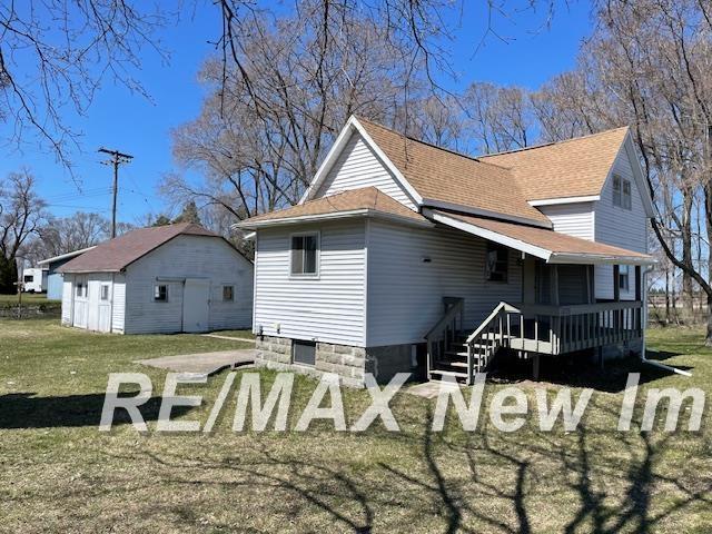 5225 N Vassar Rd, Akron, MI 48701 - rear view of house with a lawn, an outdoor structure, a deck, and a shingled roof
