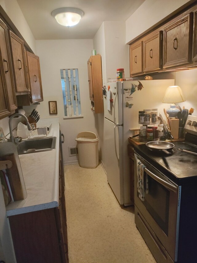 6689 Andersonville Rd Unit 29, Clarkston, MI 48346 - kitchen with stainless steel electric stove, a sink, freestanding refrigerator, and brown cabinets