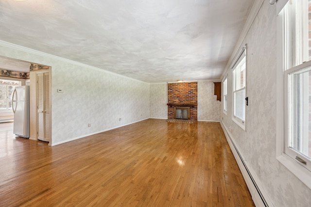 2050 Rowe Rd, Milford, MI 48380 - unfurnished living room with a baseboard heating unit, a wealth of natural light, hardwood / wood-style floors, and a fireplace