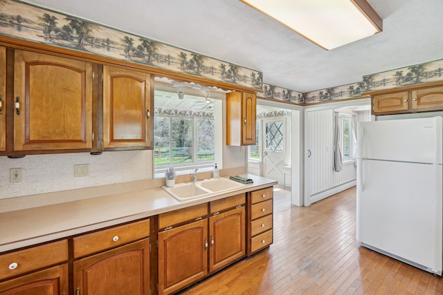 2050 Rowe Rd, Milford, MI 48380 - kitchen with a sink, a baseboard heating unit, freestanding refrigerator, light wood finished floors, and light countertops