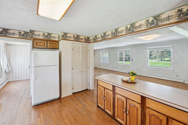2050 Rowe Rd, Milford, MI 48380 - kitchen with light wood-style flooring, freestanding refrigerator, wallpapered walls, a baseboard heating unit, and light countertops