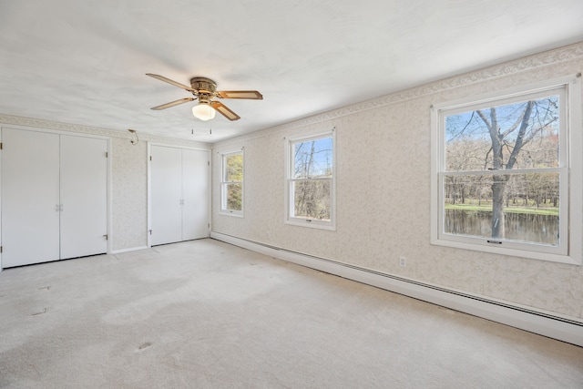 2050 Rowe Rd, Milford, MI 48380 - unfurnished bedroom with a ceiling fan, wallpapered walls, two closets, a baseboard heating unit, and light carpet