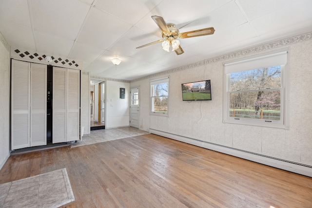 2050 Rowe Rd, Milford, MI 48380 - spare room featuring a baseboard heating unit, ceiling fan, and wood finished floors
