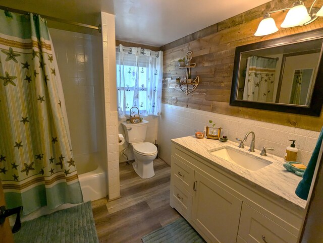 full bathroom featuring wood walls, wood finished floors, vanity, toilet, and shower / bath combo with shower curtain