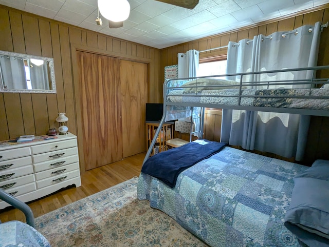 bedroom with wood walls, wood finished floors, and a closet