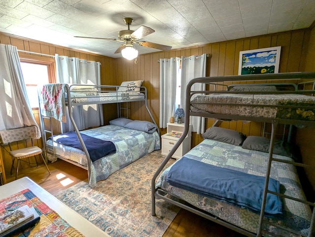 bedroom featuring wooden walls, wood finished floors, and ceiling fan