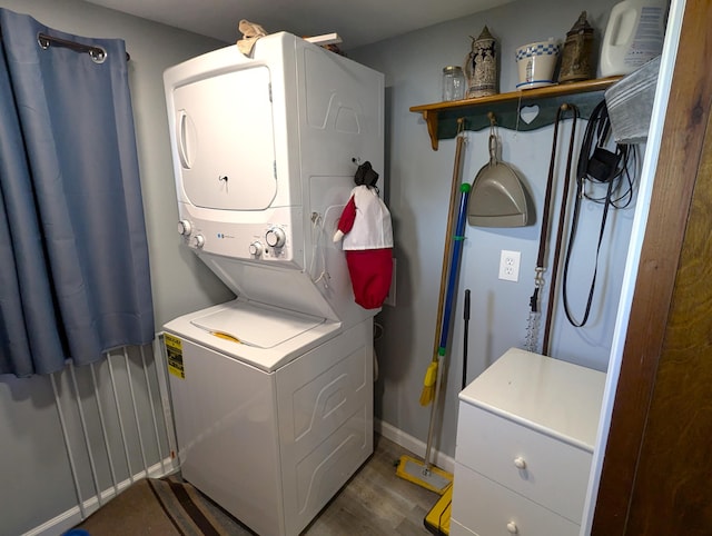 laundry area featuring baseboards, wood finished floors, stacked washer and dryer, and laundry area