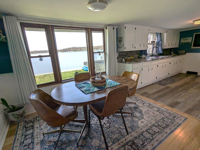 dining area with dark wood-type flooring and a water view
