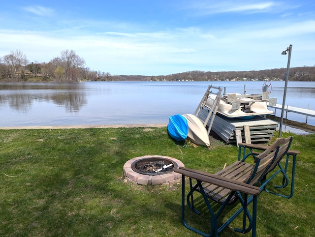 view of dock featuring a lawn, a water view, and an outdoor fire pit