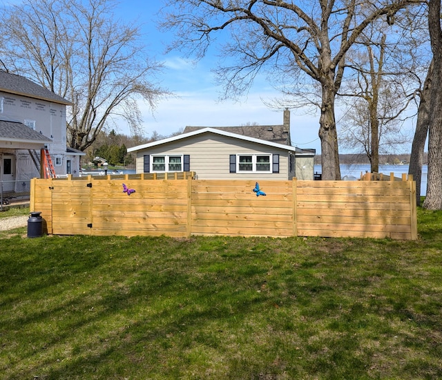exterior space featuring a yard, a chimney, a water view, and fence