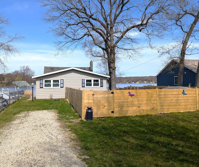 view of home's exterior with a chimney, fence, and a yard