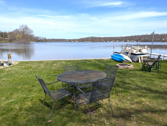 view of dock with a lawn, a water view, and an outdoor fire pit