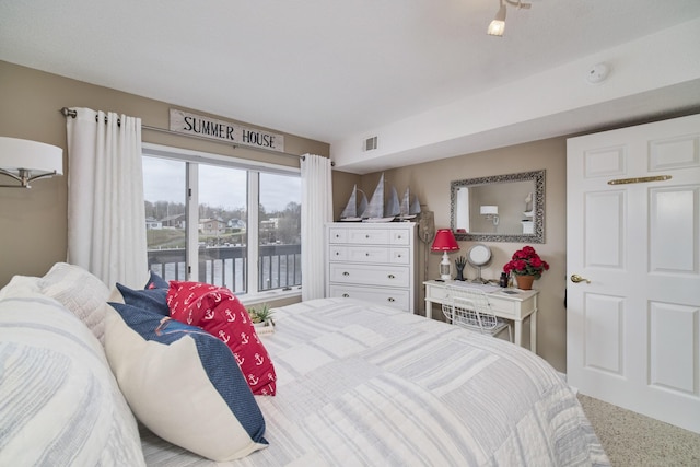 bedroom with visible vents and a water view