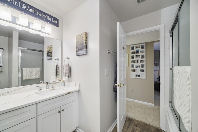 full bath featuring a shower with shower door, wood finished floors, baseboards, and vanity