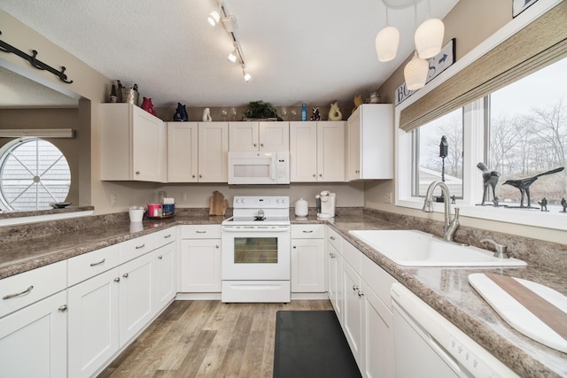 kitchen with white cabinets, light wood-style floors, a sink, and white appliances