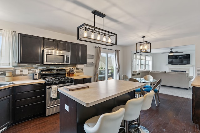 8079 Wildwood Ln, White Lake, MI 48386 - kitchen featuring appliances with stainless steel finishes, light countertops, dark wood finished floors, pendant lighting, and decorative backsplash