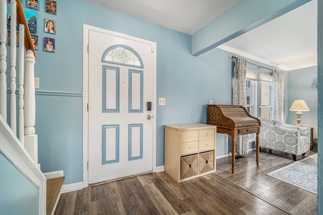 foyer entrance with wood finished floors, beam ceiling, baseboards, and stairway