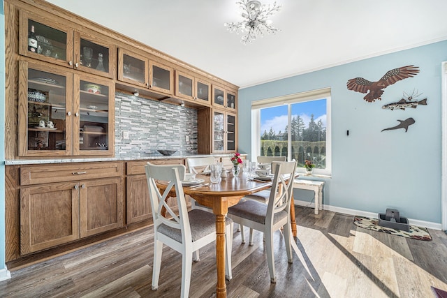 dining room with dark wood-type flooring, baseboards, ornamental molding, and an inviting chandelier