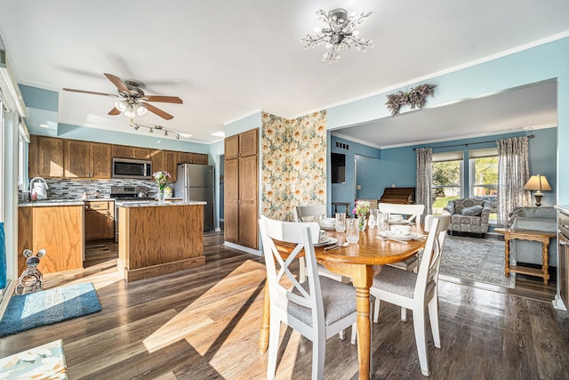 dining area featuring a ceiling fan, rail lighting, dark wood-type flooring, and crown molding