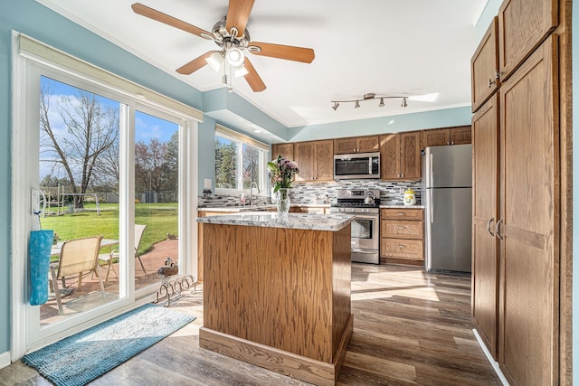 kitchen featuring ornamental molding, backsplash, appliances with stainless steel finishes, and wood finished floors
