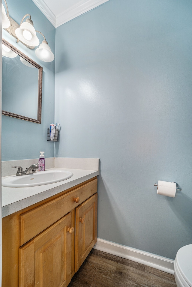 bathroom with wood finished floors, vanity, baseboards, toilet, and ornamental molding