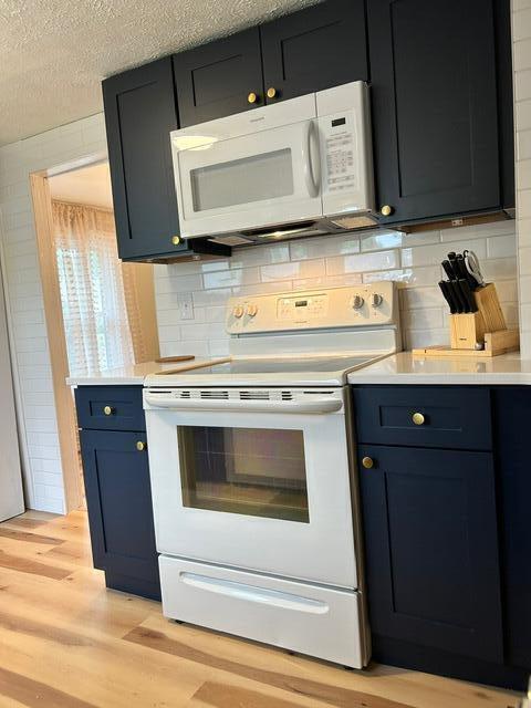 21 River St, Niles, MI 49120 - kitchen featuring light countertops, tasteful backsplash, light wood finished floors, and white appliances