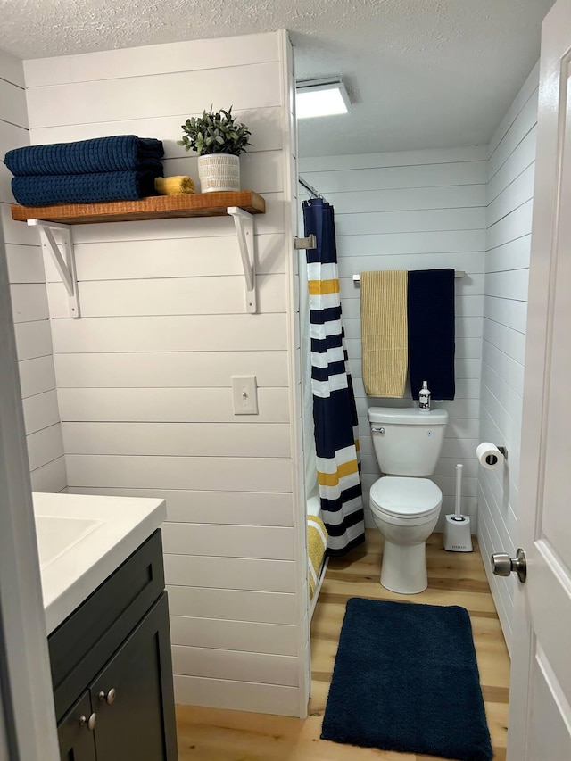 21 River St, Niles, MI 49120 - bathroom featuring a textured ceiling, toilet, wood finished floors, wooden walls, and vanity