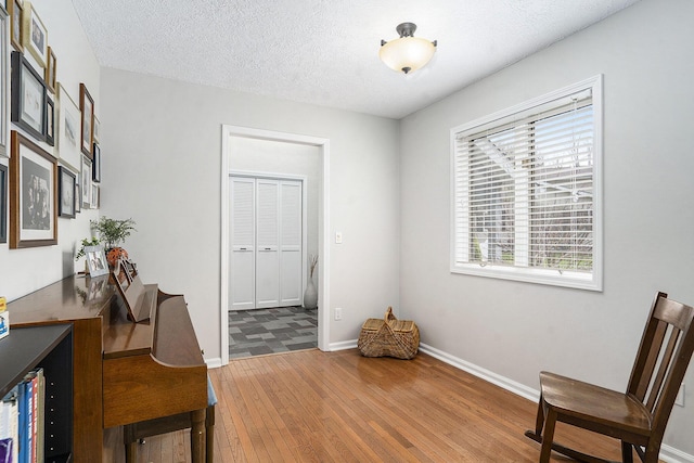 living area featuring baseboards, a textured ceiling, and hardwood / wood-style flooring