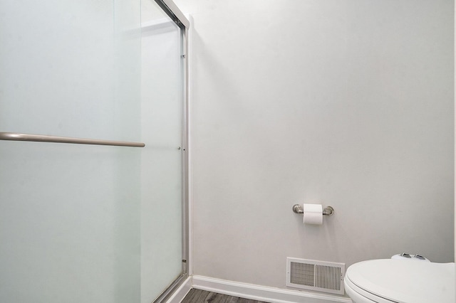 full bathroom featuring a shower stall, wood finished floors, visible vents, toilet, and baseboards
