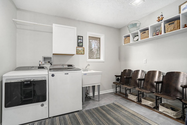 washroom with cabinet space, washer and clothes dryer, and a textured ceiling