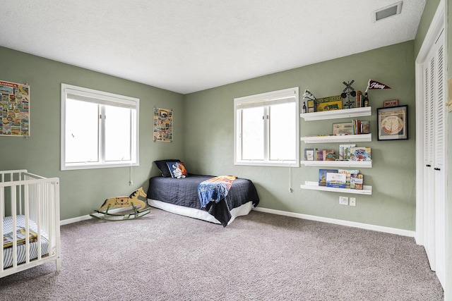 carpeted bedroom featuring baseboards, visible vents, and a closet