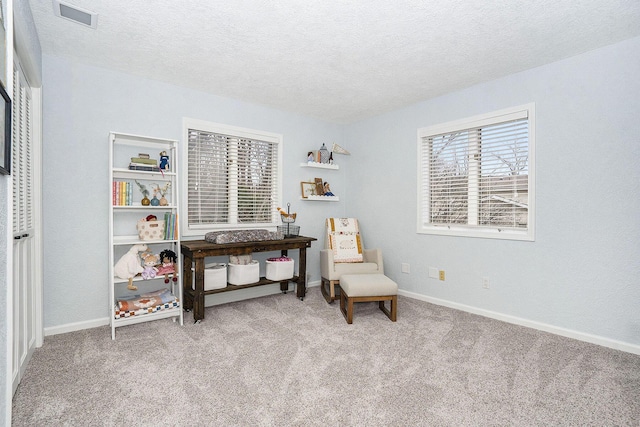 sitting room with baseboards, visible vents, carpet floors, and a textured ceiling