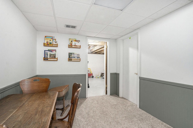 carpeted home office featuring a paneled ceiling, visible vents, and a wainscoted wall