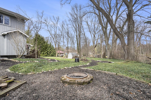 view of yard featuring an outdoor fire pit, an outbuilding, and a storage shed
