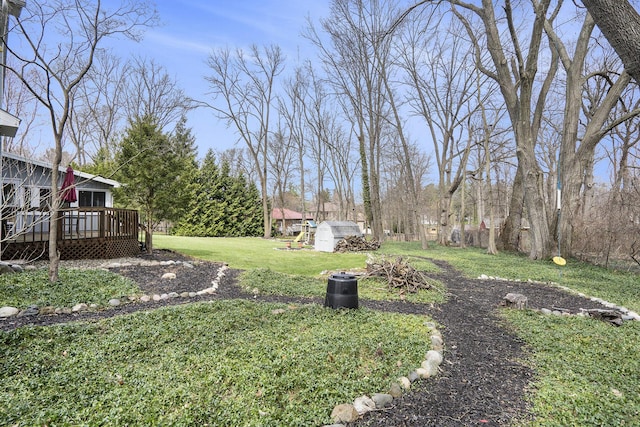 view of yard featuring a storage unit, an outbuilding, and a deck