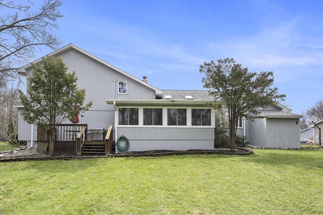 rear view of house featuring a lawn, a wooden deck, a sunroom, and a chimney