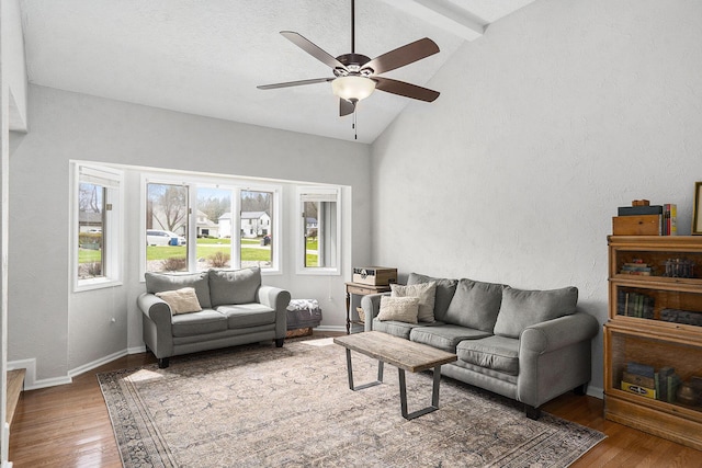 living area featuring lofted ceiling with beams, a textured wall, hardwood / wood-style floors, and ceiling fan