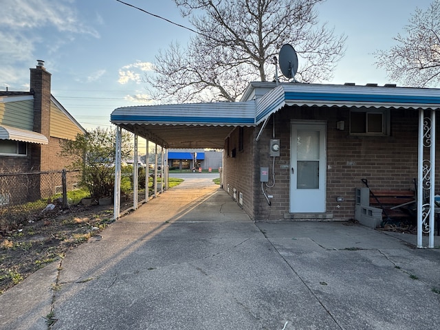 exterior space featuring brick siding, fence, driveway, and an attached carport