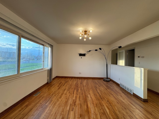 unfurnished room with baseboards, light wood finished floors, and visible vents