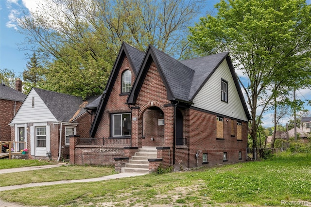 12061 Nashville St, Detroit, MI 48205 - tudor-style house with brick siding, a front lawn, and a shingled roof