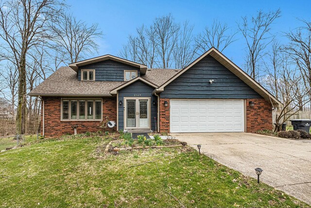 2569 Ridgewood Trl, Berrien Springs, MI 49103 - view of front facade with concrete driveway, fence, a garage, brick siding, and a front yard