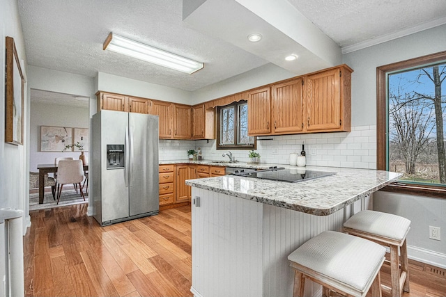 2569 Ridgewood Trl, Berrien Springs, MI 49103 - kitchen featuring light wood-type flooring, a wealth of natural light, a peninsula, a textured ceiling, and stainless steel refrigerator with ice dispenser