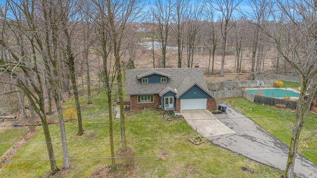 2569 Ridgewood Trl, Berrien Springs, MI 49103 - view of front facade featuring driveway, fence, brick siding, an attached garage, and a front yard