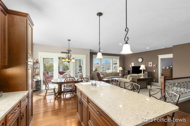 6501 Andres Xing Unit 14, Grandville, MI 49418 - kitchen featuring pendant lighting, a kitchen island, light wood-style floors, and light stone counters