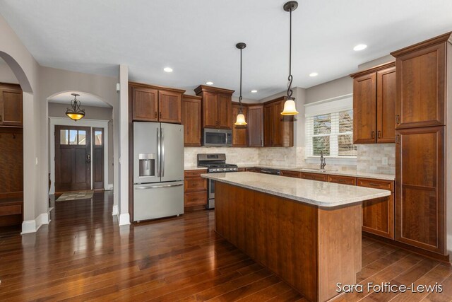 6501 Andres Xing Unit 14, Grandville, MI 49418 - kitchen featuring a sink, decorative backsplash, arched walkways, stainless steel appliances, and dark wood finished floors