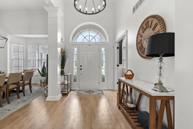2693 Sanctuary Dr, Stevensville, MI 49127 - foyer entrance with decorative columns, a towering ceiling, visible vents, an inviting chandelier, and wood finished floors